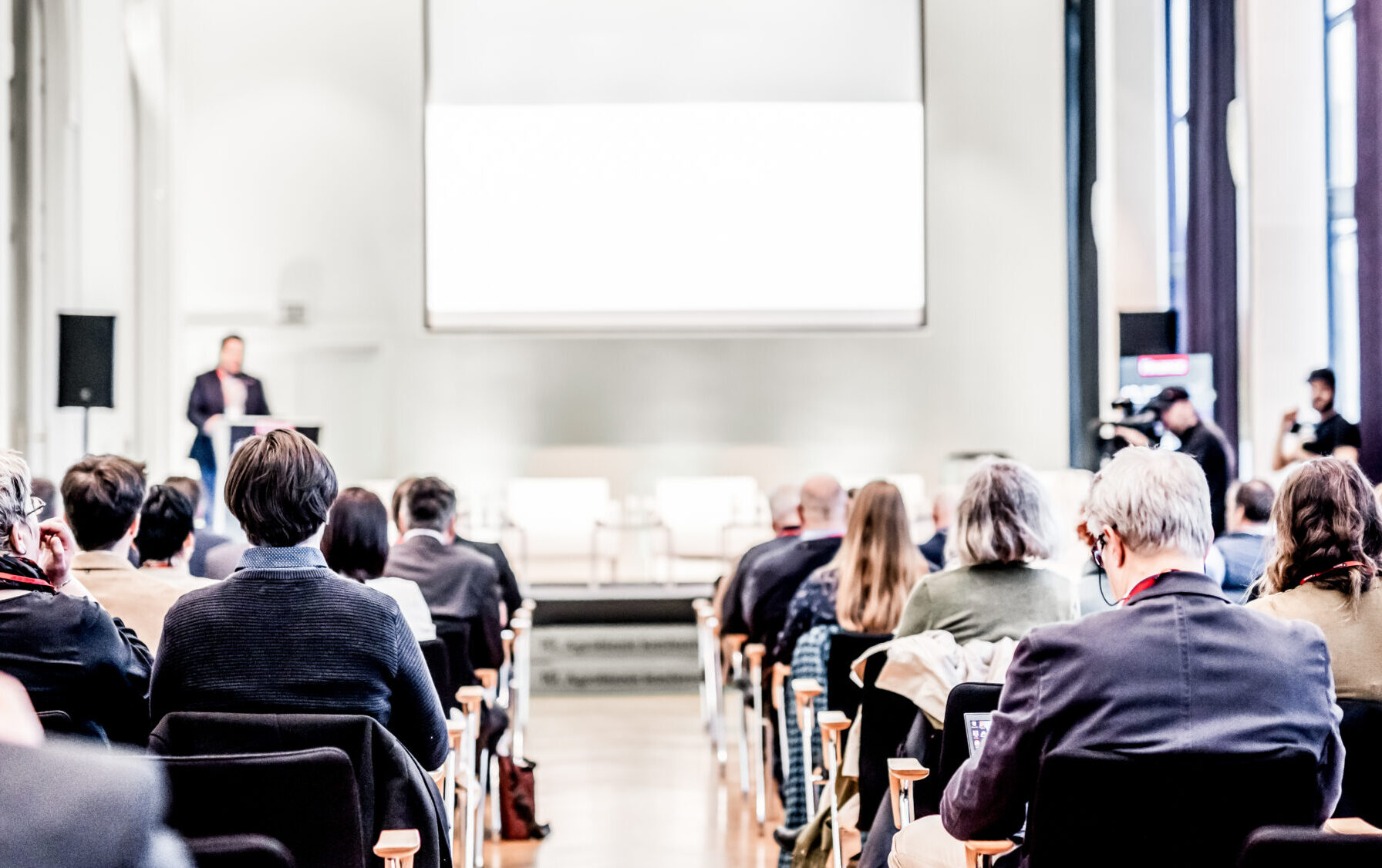 Speaker giving a talk in conference hall at business event. Rear view of unrecognizable people in audience at the conference hall. Business and entrepreneurship concept